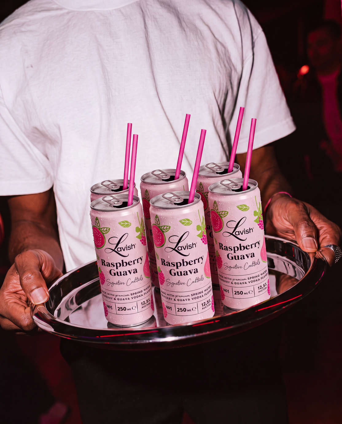 Een dienblad met Lavish Raspberry Guava-blikjes en roze rietjes